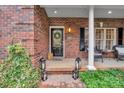 Inviting front porch features brick accents, black door with glass, decorative lanterns, and lovely greenery at 271 Lockhard Cir, Troutman, NC 28166