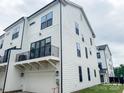 Modern townhouse with white siding, black window trim, and a balcony above the garage at 12110 Storm Ln # 49, Charlotte, NC 28277