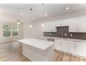 The spacious kitchen has an island, modern appliances, and dark backsplash at 9251 Eleanor Dr, Charlotte, NC 28214
