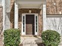 Exterior shot showcasing the front door with brick siding and decorative bushes enhancing the entrance appeal at 14121 Winford Ln, Charlotte, NC 28262