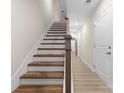 Bright hallway with hardwood floors leads to a staircase with wood treads and a white painted risers at 1916 Irma St, Charlotte, NC 28216