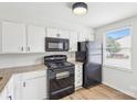 Bright kitchen features white cabinets, granite countertops and black appliances at 9424 Lexington Cir # F, Charlotte, NC 28213