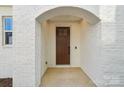 Inviting entryway featuring a classic wood door, brick walls, and a charming arched entrance at 817 Terra Dr, Tega Cay, SC 29708