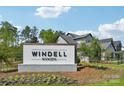 Windell Woods community sign nestled in a landscaped area with trees and newer style homes in the background at 821 Terra Dr, Tega Cay, SC 29708