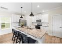 Bright kitchen with white cabinets, granite countertops, stainless steel appliances, and a spacious island with barstool seating at 159 Tanner Loop, Troutman, NC 28166