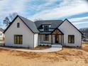 An eye-level view of a beautiful white brick house featuring black trim and a welcoming front porch with wood accents at 229 Golf Course Rd, Maiden, NC 28650