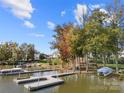 Picturesque waterfront view featuring a private boat dock with multiple boats, mature trees, and lake access at 25566 Seagull Dr, Lancaster, SC 29720
