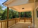 View of the covered porch with wooden railing and floor, perfect for enjoying the peaceful, wooded setting at 315 Bonaventure Dr, Salisbury, NC 28147