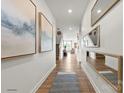 Bright hallway with wood floors, modern art, mirrors, and a view into the living room with natural light at 2561 Blue Sky Meadows Dr, Monroe, NC 28110