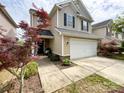View of the home's exterior, featuring a two-car garage, lovely landscaping, and a walkway leading to the front door at 1096 Mountain Laurel Ct, Matthews, NC 28104