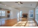 Open-concept living room with hardwood floors, brick fireplace, vaulted ceilings, and adjoining kitchen at 117 Eagle Ct, Mooresville, NC 28117