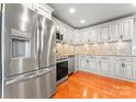 Bright kitchen with stainless steel refrigerator, oven, dishwasher, granite countertops, mosaic backsplash, and wood floors at 138 Wyanoke Ave, Charlotte, NC 28205