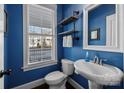 Small bathroom with blue walls, white sink and toilet, and floating shelves at 440 Luray Way, Rock Hill, SC 29730