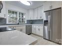 Modern kitchen with white cabinets, stainless steel appliances, and herringbone tile backsplash at 4601 Coronado Dr # C, Charlotte, NC 28212