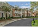 Attractive brick townhouse with a balcony, complemented by lush landscaping and a winding road at 8336 Indigo Row, Charlotte, NC 28277