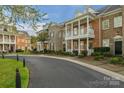 Elegant brick townhouses featuring charming balconies, complemented by mature landscaping and a curved street at 8336 Indigo Row, Charlotte, NC 28277