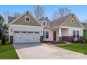 Charming single-Gathering home featuring a two-car garage, a manicured lawn, and decorative brick accents at 7169 Chamberlain Dr, Harrisburg, NC 28075