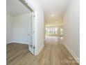 Bright hallway with wood-look flooring leading to a well-lit room with a wall of windows and a glass-paneled door at 7169 Chamberlain Dr, Harrisburg, NC 28075