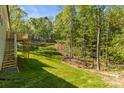 Exterior shot of the backyard's green lawn, wooden deck with stairs, and surrounding mature trees at 3146 Captains Cove Ln, Lincolnton, NC 28092