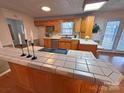 Eat-in kitchen features wood cabinets and a breakfast bar with tile countertops at 115 Turner St, Lincolnton, NC 28092