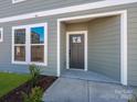 Charming covered entrance with a gray front door, complemented by a window allowing natural light into the foyer at 145 Halite Way, Waxhaw, NC 28173