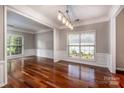 Open-concept living room with windows, wainscotting, and hardwood floors at 107 Monterey Dr, Mooresville, NC 28117