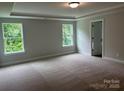 Spacious bedroom with plush carpet, large windows offering serene views, and a tray ceiling at 5115 Heathland Dr # 47, Charlotte, NC 28215