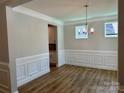 Elegant dining room with decorative wainscoting, hardwood floors, and a stylish chandelier at 5115 Heathland Dr # 47, Charlotte, NC 28215