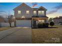 Charming two-story home featuring stone accents, a two-car garage, and a well-maintained front yard at dusk at 8007 April Ln, Matthews, NC 28104