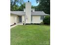 Charming single-story home features a manicured lawn, gray door, and light yellow siding at 11800 Five Cedars Rd, Charlotte, NC 28226