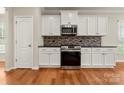 A kitchen with stainless steel appliances, granite countertops, white cabinets, and a unique mosaic backsplash at 13929 Tilesford Ln, Huntersville, NC 28078