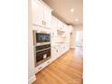 Modern kitchen with stainless steel appliances, white cabinetry, and hardwood flooring at 7928 Cedarsmith Ct, Charlotte, NC 28217
