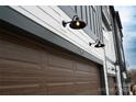 Close-up view of a two-car garage with updated carriage style door and modern lighting fixtures at 7940 Cedarsmith Ct, Charlotte, NC 28217