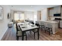 Bright open-plan living/dining area with hardwood floors and modern decor flowing to kitchen at 1602 Village Grove Ln, Monroe, NC 28110