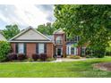 Beautiful two-story brick home with a well-maintained lawn and mature tree shading the facade at 9618 Belloak Ln, Waxhaw, NC 28173