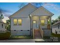 Charming new construction home at dusk featuring white siding, brick stairs, and a welcoming covered front porch at 1105 Kenly St, Salisbury, NC 28144