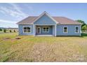 Rear exterior view of the light blue home with covered patio, and level yard at 220 W Lawyers Rd, Monroe, NC 28110