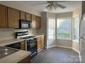 Bright kitchen with wood cabinets, black appliances, gray countertops, wood-style flooring, and a bay window at 6017 Treetop Ct, Charlotte, NC 28212