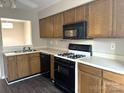 Well-lit kitchen featuring wood cabinets, laminate countertops, black appliances, and wood-style flooring at 6017 Treetop Ct, Charlotte, NC 28212