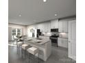 Modern kitchen with white cabinets, island, stainless steel appliances, and gray flooring at 216 Alden Ct, Shelby, NC 28152