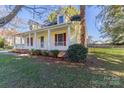 Quaint yellow house featuring red shutters and a porch with a brick chimney and landscaped lawn at 2216 Lowell Bethesda Rd, Gastonia, NC 28056