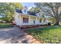 Inviting yellow home featuring red shutters, a cozy front porch, and a convenient driveway at 2216 Lowell Bethesda Rd, Gastonia, NC 28056