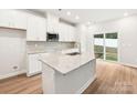 White kitchen features a large island with granite countertops and stainless steel appliances at 4011 Bufflehead Dr, Charlotte, NC 28269