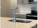 Close-up of kitchen featuring stainless steel appliances, quartz countertops, tile backsplash, and gray cabinets at 4019 Bufflehead Dr, Charlotte, NC 28269