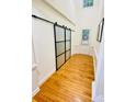 Bright hallway featuring hardwood floors and a stylish frosted glass sliding barn door at 14027 Grand Traverse Dr, Charlotte, NC 28278