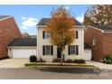 Tan brick home with black shutters, attached garage, and tree in front at 548 Summerfield Pl, Belmont, NC 28012