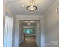 Bright hallway featuring hardwood floors, crown molding, and a view into the spacious living areas at 9130 Dulwich Dr # Ken0079, Charlotte, NC 28215