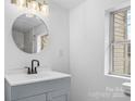 Stylish bathroom with a sleek vanity, round mirror, and natural light from the window at 612 E E St, Newton, NC 28658