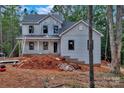 Two-story new construction home with light gray siding and black window frames ready for brick on a large wooded lot at 4615 Yellow Poplar Ln, Concord, NC 28025