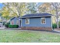 Side view of a charming blue house with manicured landscaping and brick foundation at 13446 Idlefield Ln, Matthews, NC 28105